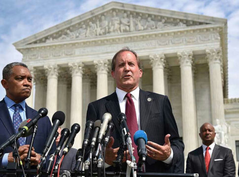 Men in suits speaking at podium outside courthouse.