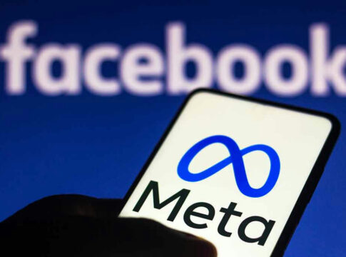 Smartphone displaying Meta logo with Facebook in background.