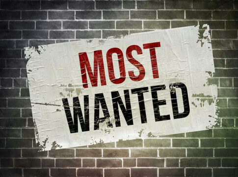 Most Wanted poster on brick wall.