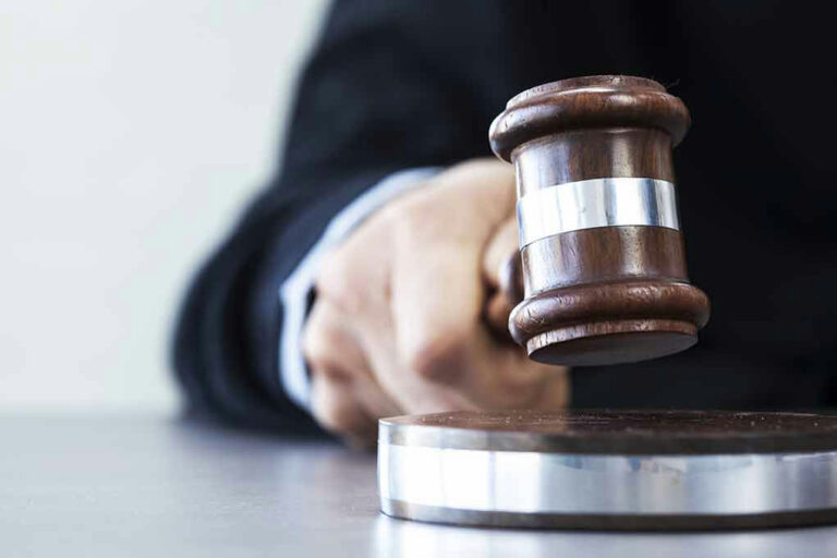 Judges hand hitting gavel on block.