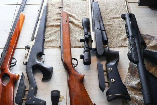Assorted rifles and shotguns laid out on a table