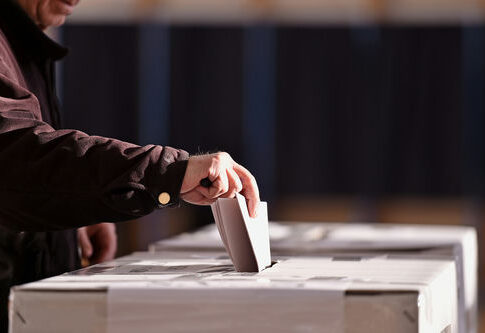 Person placing a ballot into a voting box