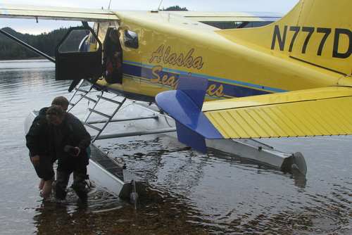 Passengers disembarking from a yellow seaplane on a calm lake